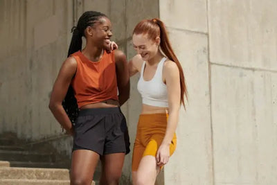 Two women stand side by side after a run around a sports complex wearing their American made activewear clothing.