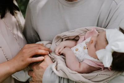 A mother and father hold a newborn in their 100% cotton American made blanket. 