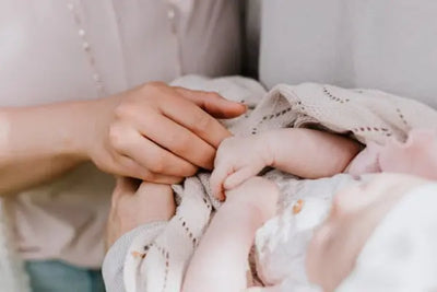 A father and mother comfort a baby in their arms with an American made baby blanket. 