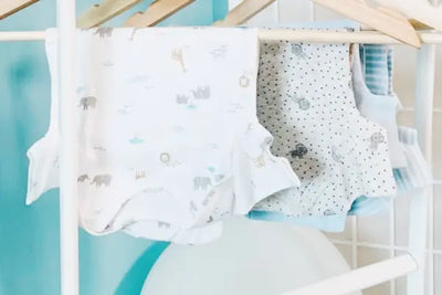 Two baby bodysuits hanging from a hanger. Each was made in America with organic cotton.