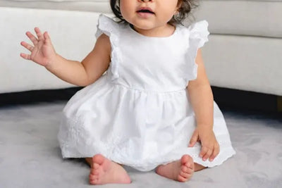 A baby wearing a white dress.