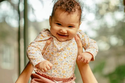 A baby wearing a floral long sleeve shirt.