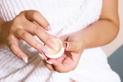 A mom holding baby skin care products on her hand before applying it on her baby's skin. She chose this baby skin care because it was fabricated in a lab in the USA.