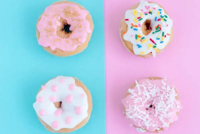 A selection of baked goods that were made in America. Four sprinkled donuts sit on a plate. 