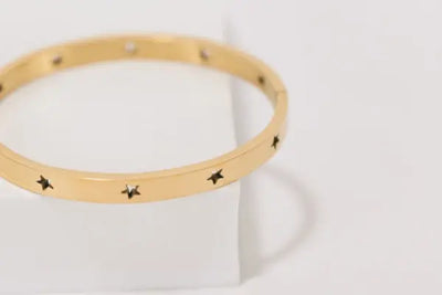 A gold bangle bracelet with silver stars.