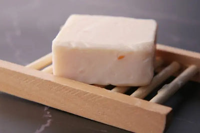 A bar of handcrafted soap sits on a crafted wooden soap holder. 