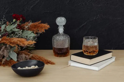 A whiskey bottle and serving glass sit on a table.