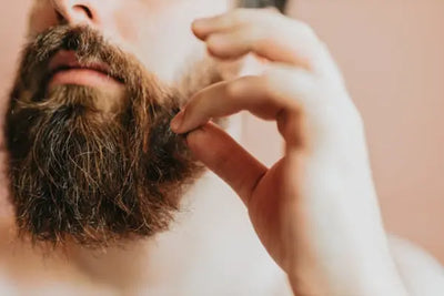 A man brushes his beard with beard care supplies that were made in America.