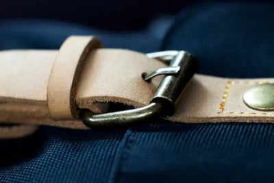 An American made leather belt sits on a blue cloth. 
