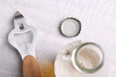 A bottle opener with a cap sitting on a table.