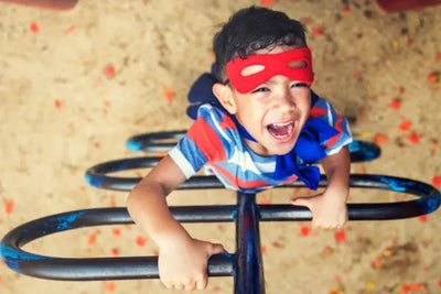 A boy climbing a ladder wearing a superhero mask and cape.