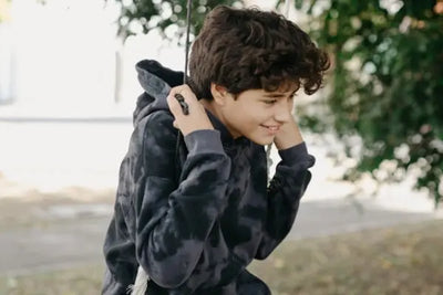 A boy on a swing wearing an American-made hoodie.