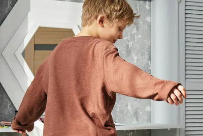 A young boy wearing a brown long-sleeve shirt.