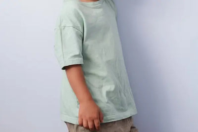 A young boy wears a teal t-shirt that was made in the USA.