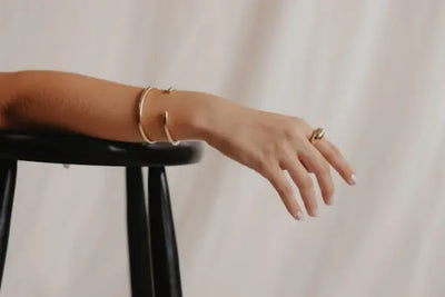 A woman's arm lies on a chair showing her bracelet.