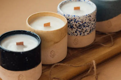 Four candles with wooden wicks that were hand poured in the United States sit side by side waiting to be lit.