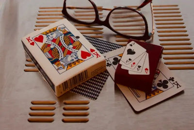 Playing cards, a deck with a king of hearts, and glasses on a table. 