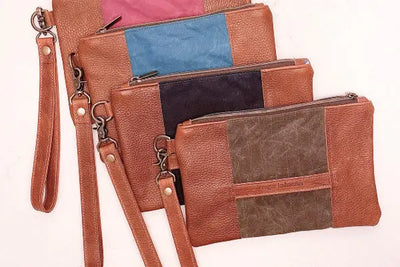 Four leather clutches sitting side by side on a table.