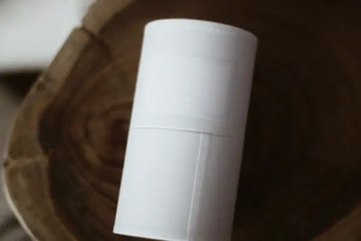 A plain white cylindrical package resting on a wooden surface.