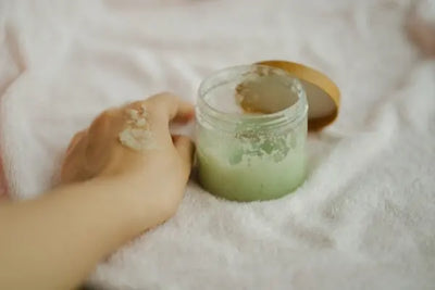 An open bottle of American made exfoliants and scrubs are being used on the skin of a person. 