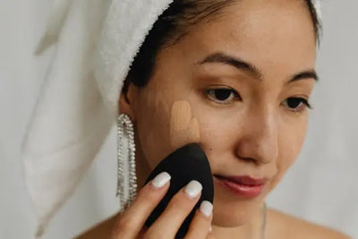 An elegant woman is applying American made face products on her face after getting out of a shower. 