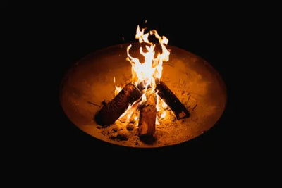 A glowing campfire surrounded by logs in a round fire pit, with bright flames dancing.