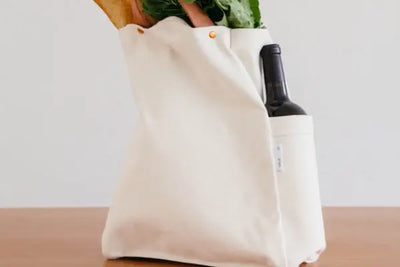 Wine and bread in a white carry bag. 