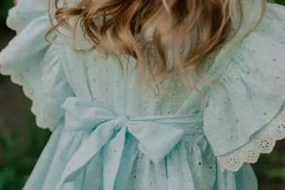 A girl wearing a knitted blue dress that was made in the USA.