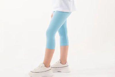 A girl wearing a white shirt and blue leggings.