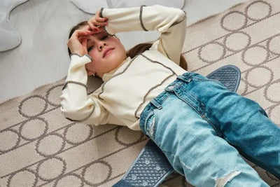 A girl sitting on a skateboard wearing an American-made long-sleeve shirt.