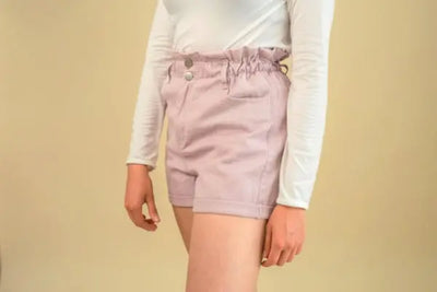 A girl wearing pink shorts and a white sweater.