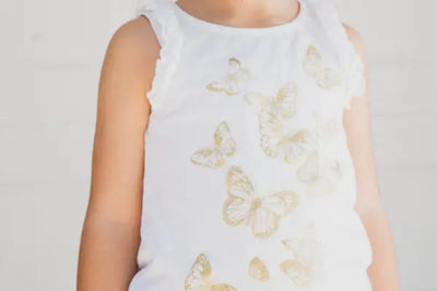 A girl wearing a butterfly white tank top that was made in America with organic cotton from Texas.