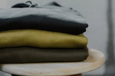 Multiple American-made hoodies sit on a chair in a clothing store.