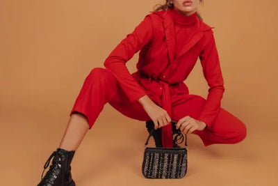 A woman wearing a red jumpsuit picking up her purse.