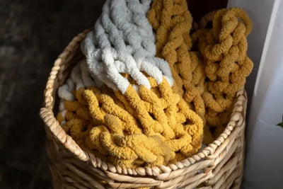A brown and white American made knitted blanket in a brown farmhouse basket.