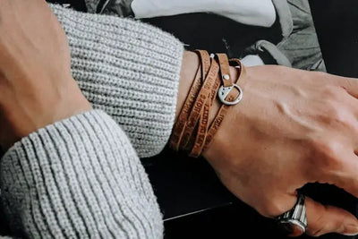 A grey sweater and tan leather bracelet made in the USA.