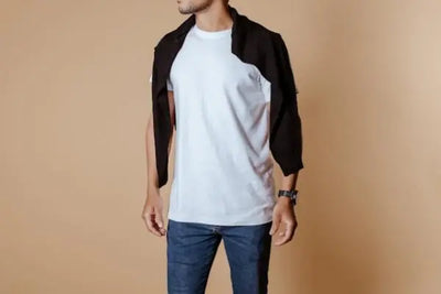 A man poses with a sweater around his shoulders while wearing an American made tee shirt.