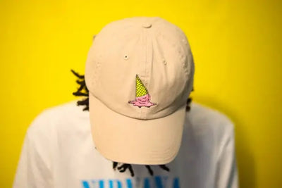 A yellow hat that is made in the USA has an ice cream cone embroidered on the front. 