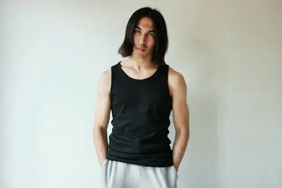 A man wearing an American made black tank top poses for a photoshoot. 
