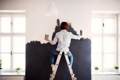 A woman painting a wall blue