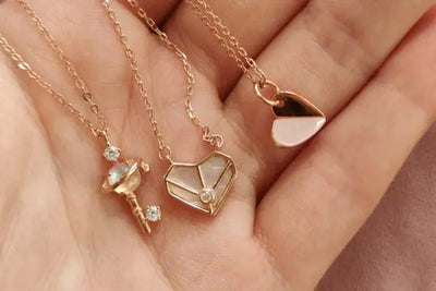 A hand holding three pendant necklaces.