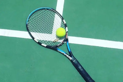 A green tennis racquet and ball on a court.