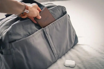 A grey travel bag with a passport with American made leather.