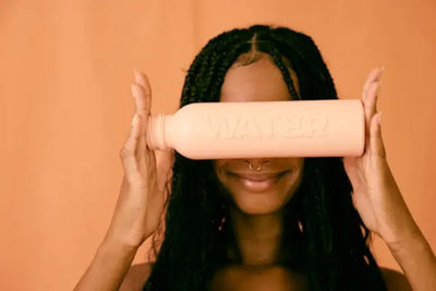 A woman holding an orange water bottle.