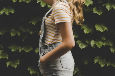 A woman wearing an American-made striped t-shirt under overalls.