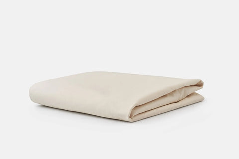 A neatly folded Cotton Single [Separate] Fitted Bed Sheet by American Blossom Linens, in a cream shade and made from luxurious USA-grown cotton, is placed on a plain white background.