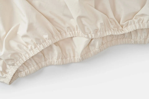 A close-up of the Cotton Single [Separate] Fitted Bed Sheet by American Blossom Linens, featuring elastic edges and crafted from USA-grown cotton, displayed on a white surface.