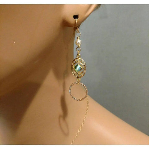 A close-up of a mannequin showcases Alexa Martha Designs’ 14 KT Gold Filled Green Crystal Hammered Circle Filigree Earrings, featuring pearl studs, green crystals, and textured gold hoops.