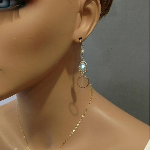 Close-up of a mannequin wearing Alexa Martha Designs 14 KT Gold Filled Green Crystal Hammered Circle Filigree Earrings, paired with a delicate gold chain necklace, against a plain gray background.