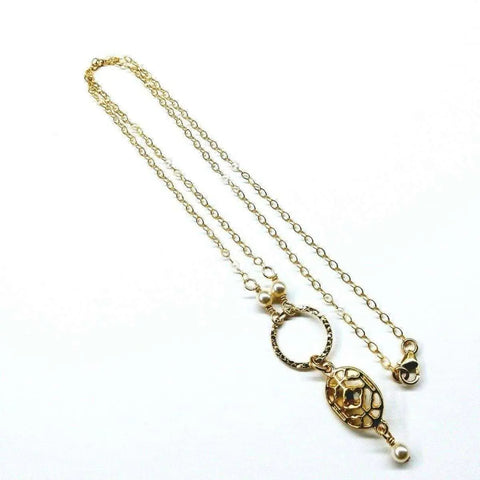 The 14K Gold-Filled Hammered Open Circle Filigree Necklace by Alexa Martha Designs features a textured circle pendant, turtle charm, Swarovski pearls, and small pearl accents. Handmade in Montana and shown on a white background.